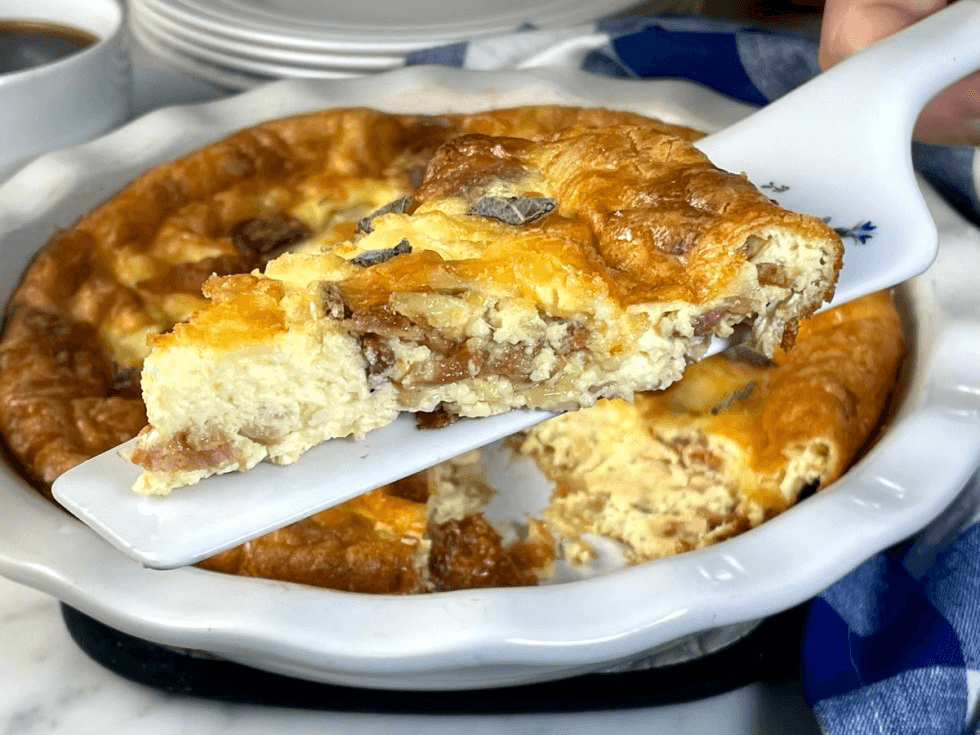A bacon quiche being held up by a spatula.
